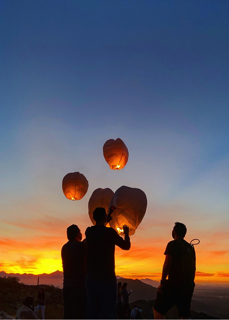 People releasing lanterns at sunset